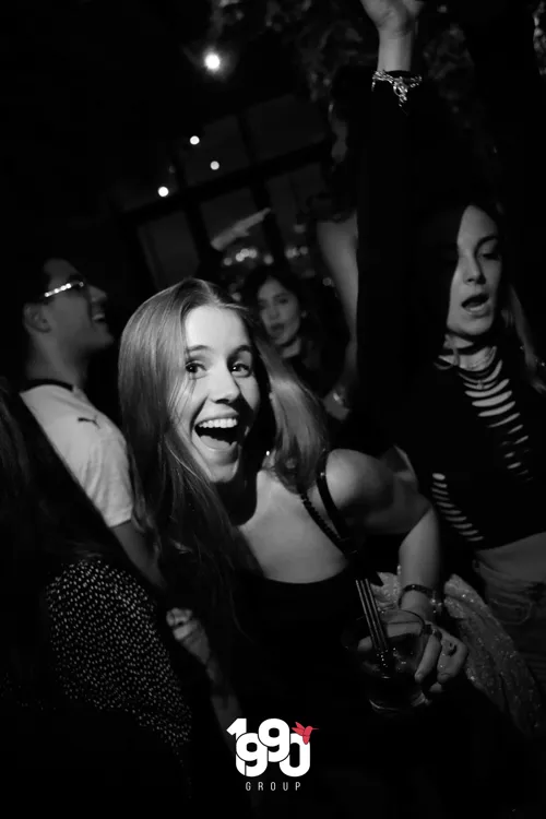 Smiling woman at a nighttime event in New York, organized by 1990 Group.