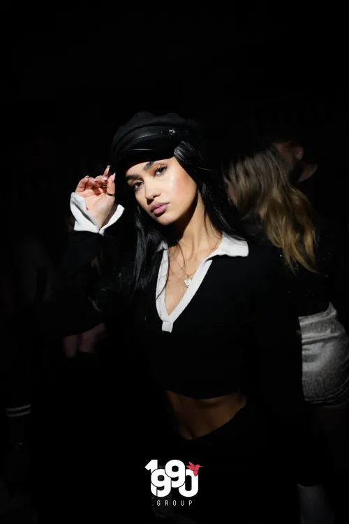 Woman posing with a hat at a nightclub in New York, organized by 1990 Group.