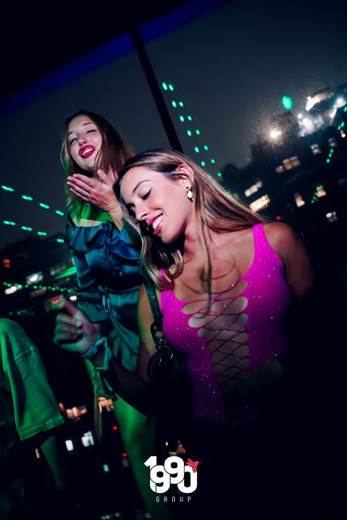 Two women dancing and enjoying themselves at a New York nightclub, hosted by 1990 Group.