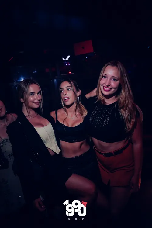 Three friends posing at a nighttime party in New York, organized by 1990 Group.