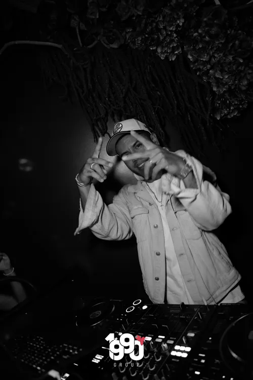 Black and white DJ pointing at the camera while mixing music at the Fuego Thursdays party hosted by 1990 Group in New York.