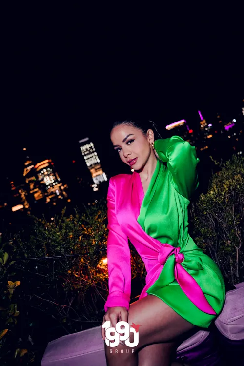 Elegant woman posing on a rooftop with the New York City skyline in the background at a private event hosted by 1990 Group.