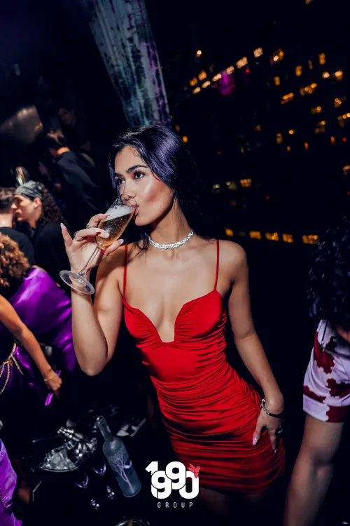 Elegant woman drinking champagne at Fuego Thursdays, a party organized by 1990 Group in New York.